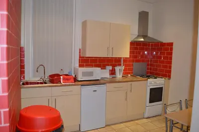 a kitchen with white appliances and a red brick wall at Ayrton House Holiday Apartments in Blackpool