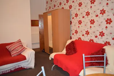a living room with a red couch and a cabinet at Ayrton House Holiday Apartments in Blackpool