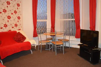 a living room with a red couch and a table at Ayrton House Holiday Apartments in Blackpool