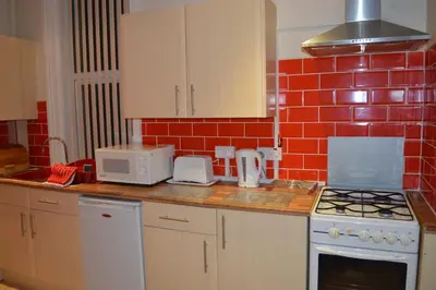 a kitchen with a red tiled wall at Ayrton House Holiday Apartments in Blackpool