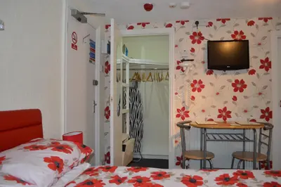 a bedroom with a bed and a table with a television on the wall at Ayrton House Holiday Apartments in Blackpool