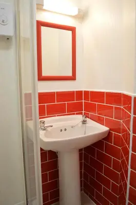 a bathroom with a white sink and red tiles at Ayrton House Holiday Apartments in Blackpool