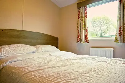 a bedroom with a large white bed and a window at Plot 188D Lakeside Cabin, Wyldecrest, Millom in Millom