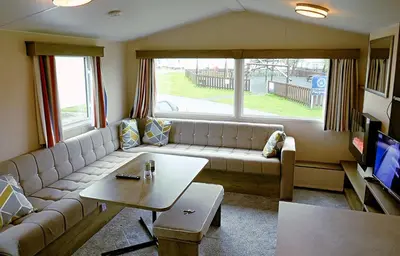 a living room with a couch and a table at Plot 188D Lakeside Cabin, Wyldecrest, Millom in Millom