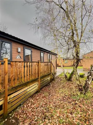 a wooden fence next to a house with a tree at Coniston View 7 in Warton