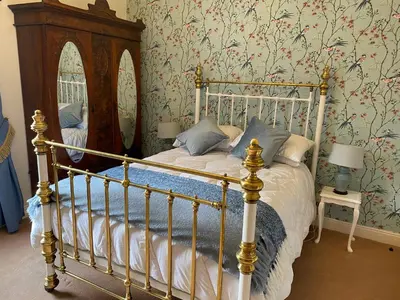 a bedroom with a canopy bed with floral wallpaper at Number 19 - Victorian Town House in Clitheroe