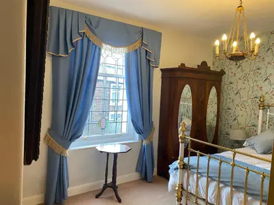 a bedroom with a bed and a window with blue curtains at Number 19 - Victorian Town House in Clitheroe