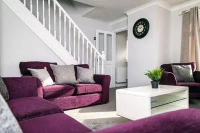 a living room with two purple couches and a clock at Mill Charm in Barrow in Furness