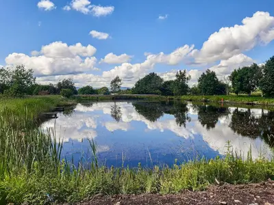 a pond with reflections of clouds in the water at Lake View - Uk36811 in Whalley