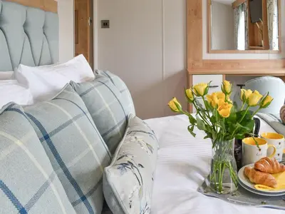 a table with a vase of flowers and a plate of bread at Lake View - Uk36811 in Whalley
