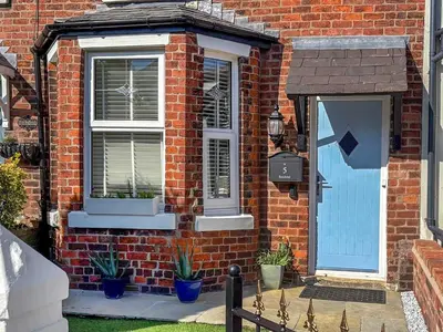 a brick house with a blue door and windows at Sandend in Lytham St Annes