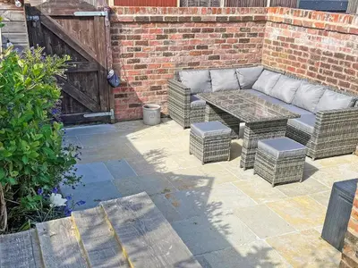 a patio with a couch and a table and a brick wall at Sandend in Lytham St Annes