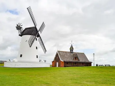 a windmill in a field next to a building at Sandend in Lytham St Annes