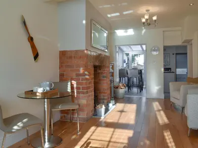 a living room with a brick fireplace and a table at Sandend in Lytham St Annes