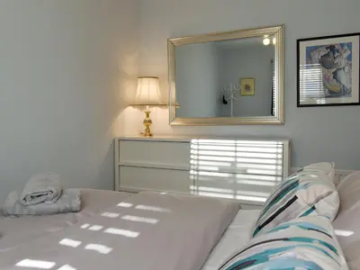 a white bedroom with a bed and a mirror at Sandend in Lytham St Annes
