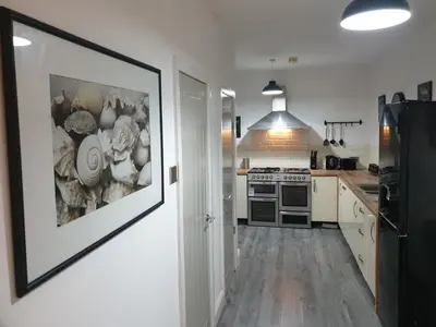a kitchen with white cabinets and a black refrigerator at Stunning 5 bed house, 2 mins to beach and town, with free parking in Blackpool