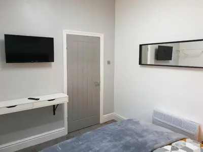 a white room with a bed and a television on the wall at Stunning 5 bed house, 2 mins to beach and town, with free parking in Blackpool