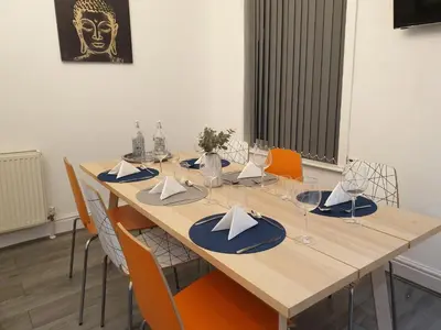 a long wooden table with chairs and napkins at Stunning 5 bed house, 2 mins to beach and town, with free parking in Blackpool
