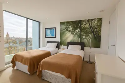 two beds in a room with a large window at Sidemersey Livings- Unmatched Panoramic Views, Secure Parking, Beautiful Balcony- A Stay to Remember in Liverpool