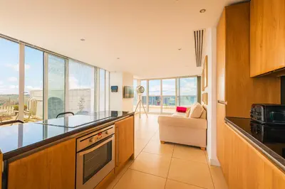 a kitchen with a view of a living room at Sidemersey Livings- Unmatched Panoramic Views, Secure Parking, Beautiful Balcony- A Stay to Remember in Liverpool