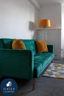 a green couch sitting in a living room at FLATZY - Modern Apartment Close to Football Stadiums in Liverpool