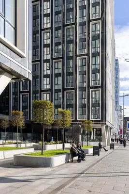 people sitting on benches in front of a tall building at Copper House in Liverpool in Liverpool