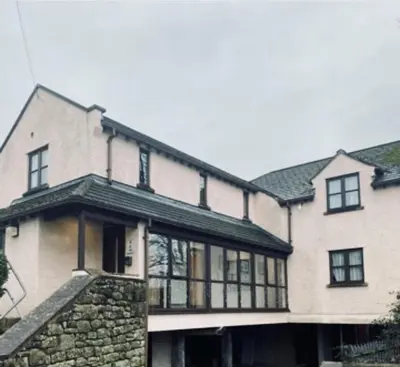 a large white house with a stone wall at The County Lodge in Carnforth