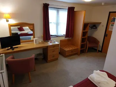 a room with a desk with a computer and a bed at The County Lodge in Carnforth