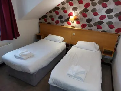 two beds in a hotel room with white sheets at The County Lodge in Carnforth