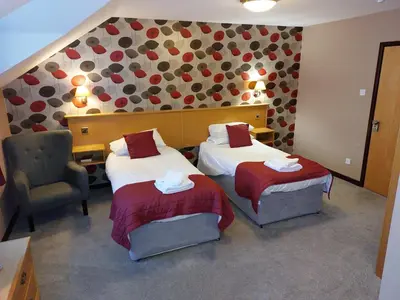 a hotel room with two beds and a chair at The County Lodge in Carnforth