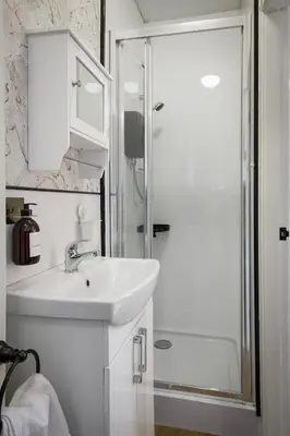 a white bathroom with a sink and a shower at Lunar Stays in Blackpool