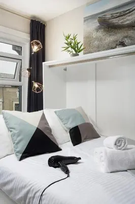 a white bed with a black remote control on it at Lunar Stays in Blackpool