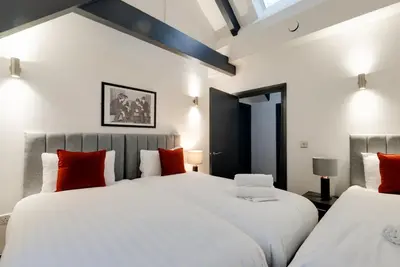 two beds in a bedroom with white and red pillows at Harrisons Aparthotel Liverpool in Liverpool