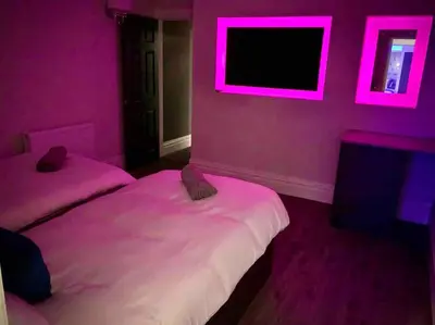 a pink room with two beds and a tv at Saltrock luxury apartment in Blackpool