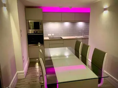 a kitchen with a table and chairs with pink lighting at Saltrock luxury apartment in Blackpool