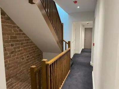 a hallway with stairs and a brick wall at The Royal Crest in Liverpool