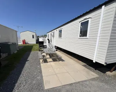 a row of benches next to a white trailer at 3 Bedroom Modern Caravan Sleeps up to 8 in Millom