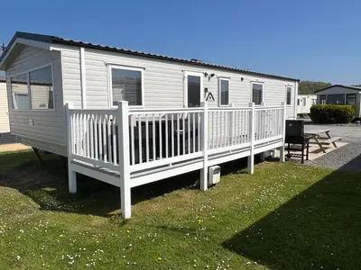 a white mobile home with a porch and a deck at 3 Bedroom Modern Caravan Sleeps up to 8 in Millom