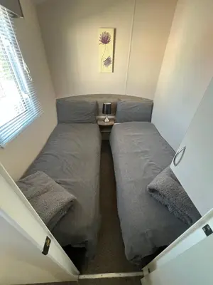 a small room with two beds and a window at 3 Bedroom Modern Caravan Sleeps up to 8 in Millom