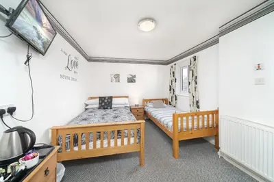 two beds in a room with white walls at Deneside Guest House in Blackpool