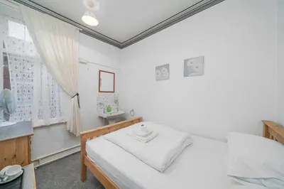 a white bedroom with a bed and a sink at Deneside Guest House in Blackpool