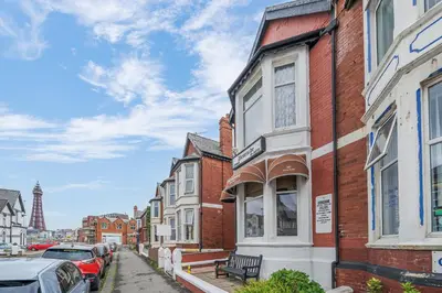 a row of houses on a city street with cars parked at Deneside Guest House in Blackpool