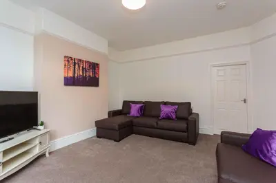 a living room with a couch and a tv at Cherry Property - Passionfruit Suite in Blackpool