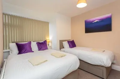 two beds in a room with purple pillows at Cherry Property - Passionfruit Suite in Blackpool