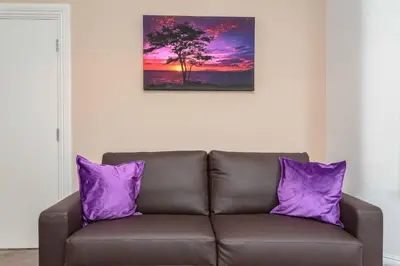 a brown couch with purple pillows in a room at Cherry Property - Passionfruit Suite in Blackpool