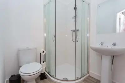 a bathroom with a shower and a toilet and a sink at Cherry Property - Passionfruit Suite in Blackpool
