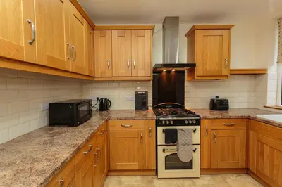 a kitchen with wooden cabinets and a stove top oven at Cherry Property - Passionfruit Suite in Blackpool