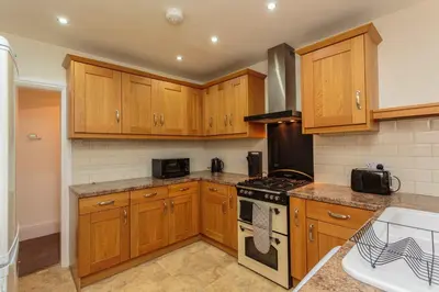 a kitchen with wooden cabinets and a stove top oven at Cherry Property - Passionfruit Suite in Blackpool