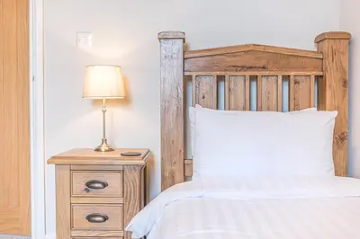 a bedroom with a bed and a lamp on a night stand at The Black Dog Cottage in Dalton in Furness