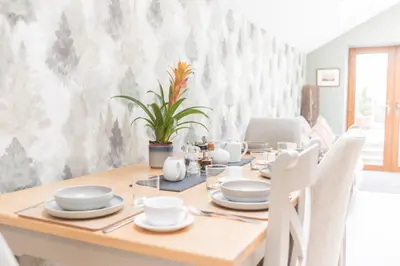 a dining room with a wooden table with white chairs at The Black Dog Cottage in Dalton in Furness
